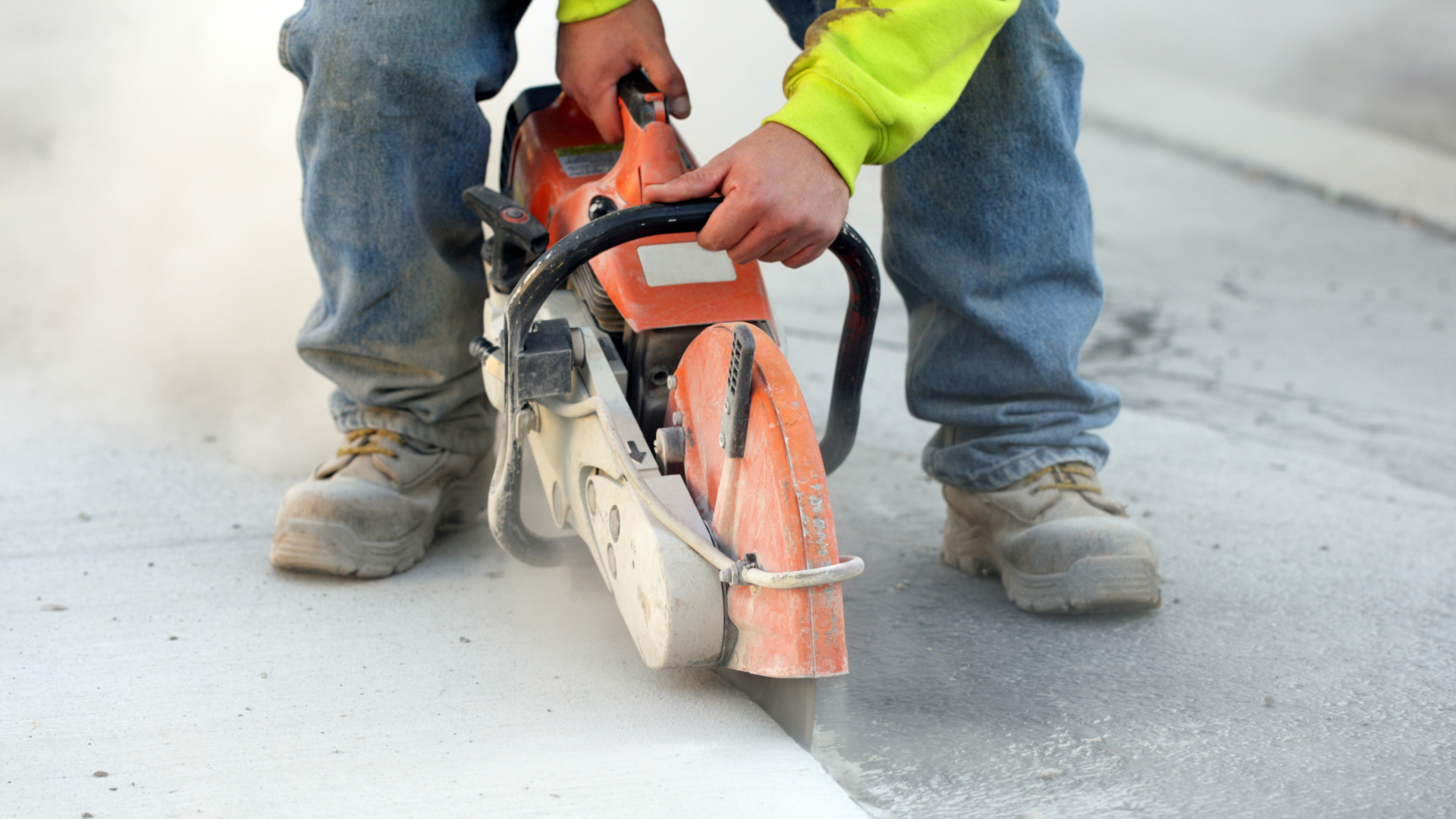A man is cutting concrete with a chainsaw.