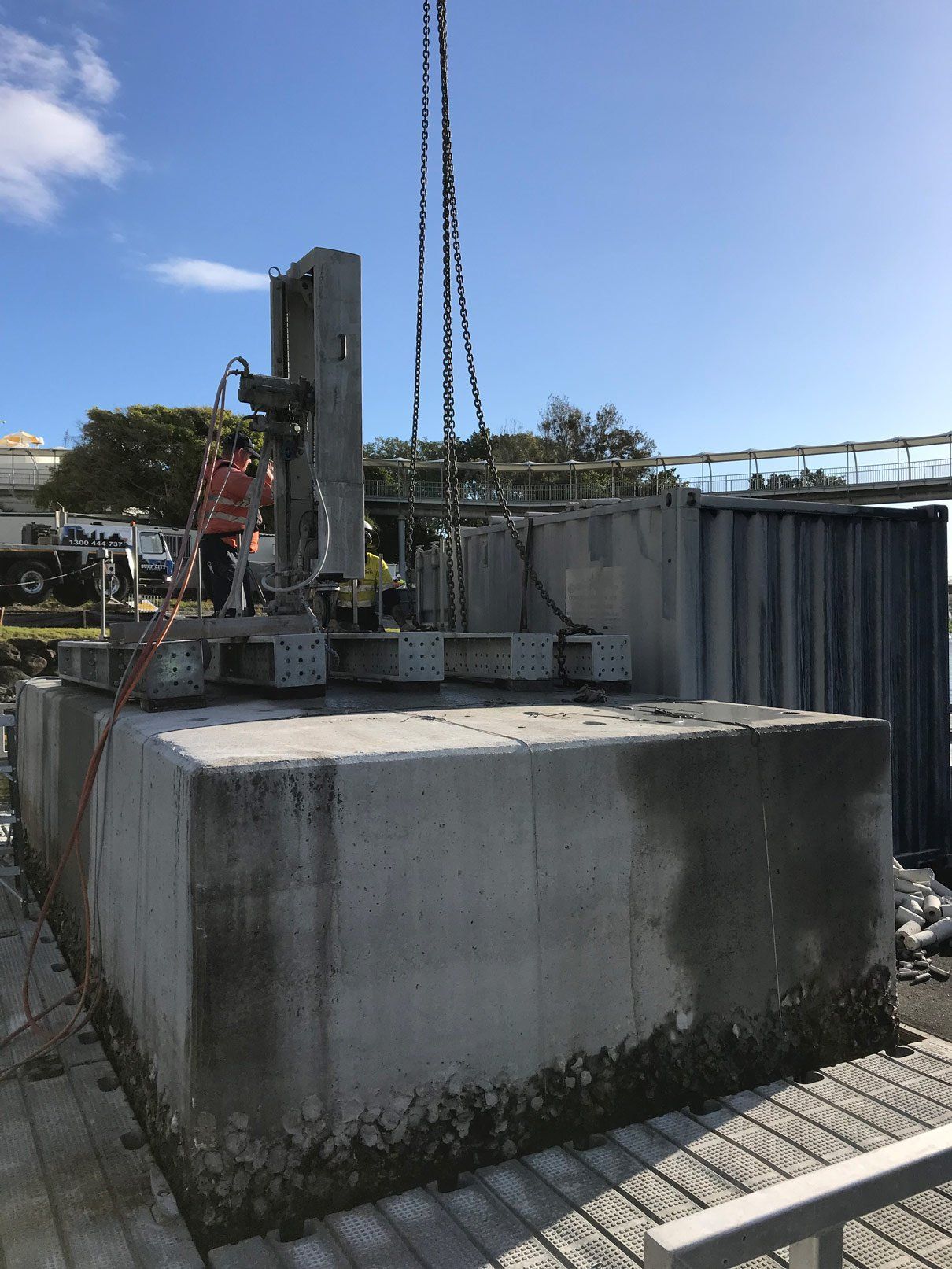 A large concrete block is being lifted by a crane.