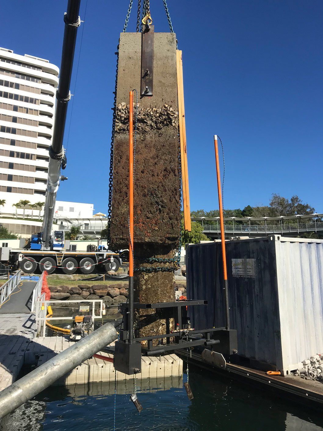 A large piece of metal is being lifted into the water by a crane.