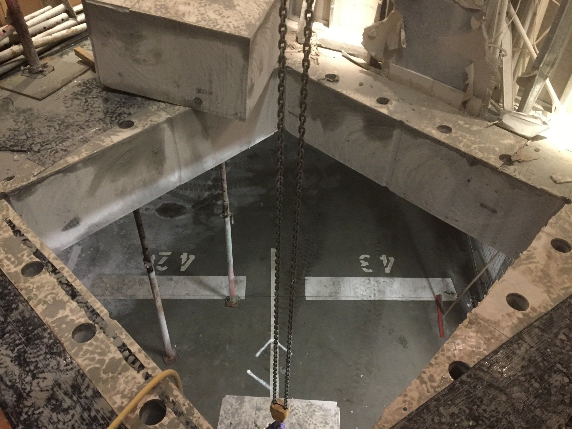 A crane is lifting a piece of concrete into a hole with a3 and a4 written on it.