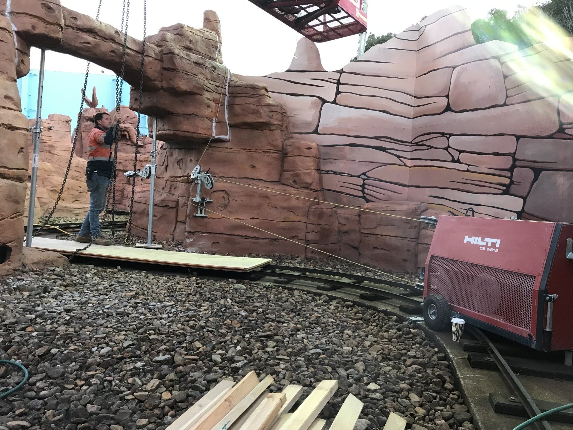 A man is standing in front of a large rock wall.