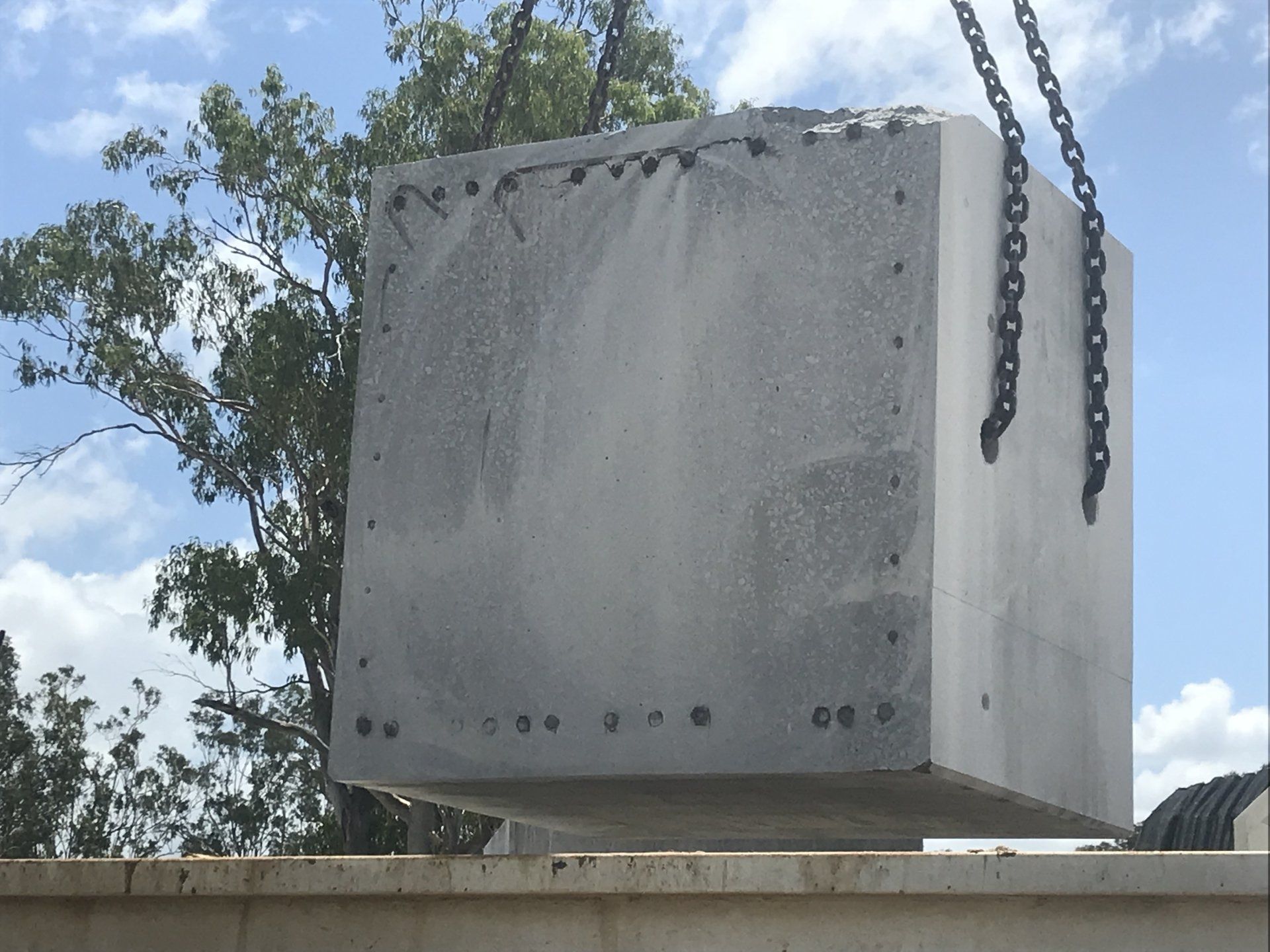A large concrete block is being lifted by chains