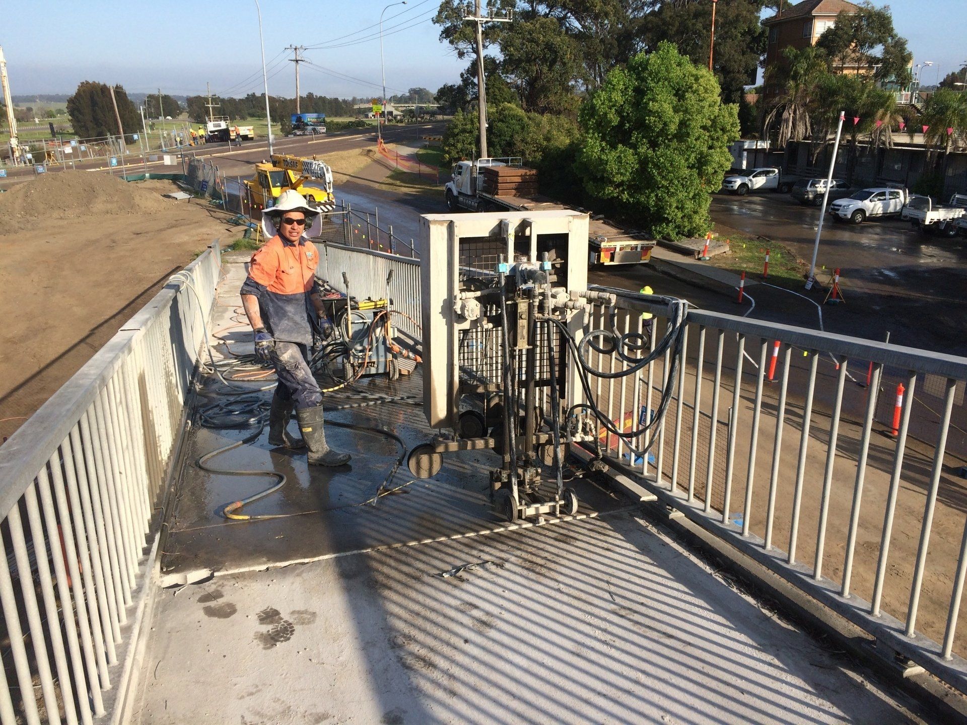 A man is cutting a bridge railing with a machine.
