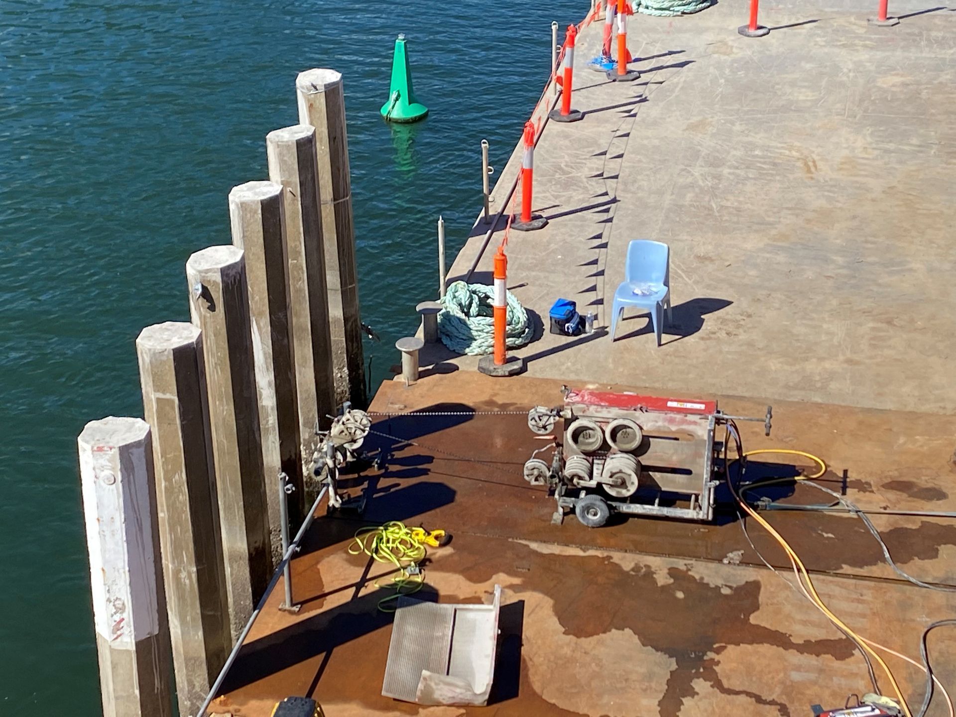 A machine is sitting on a dock next to a body of water.