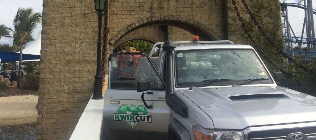 A silver truck is parked in front of a stone archway.