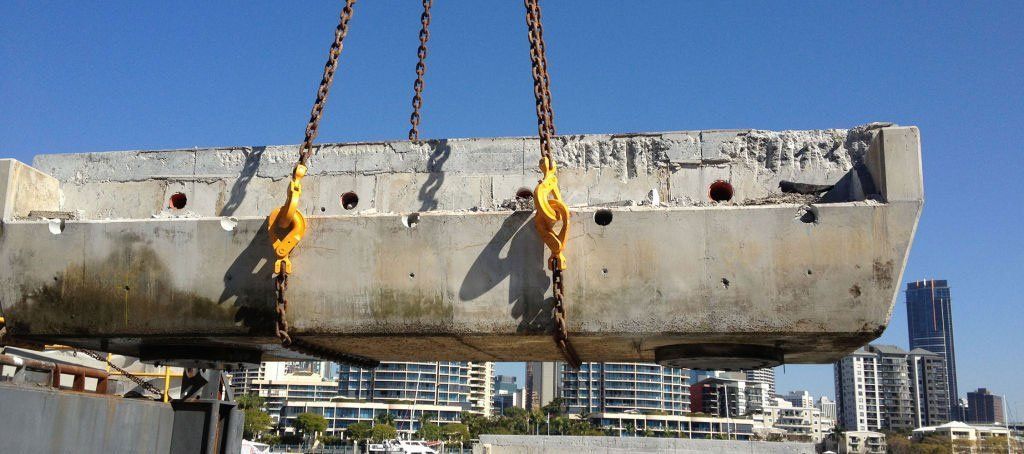 A large piece of concrete is being lifted by chains
