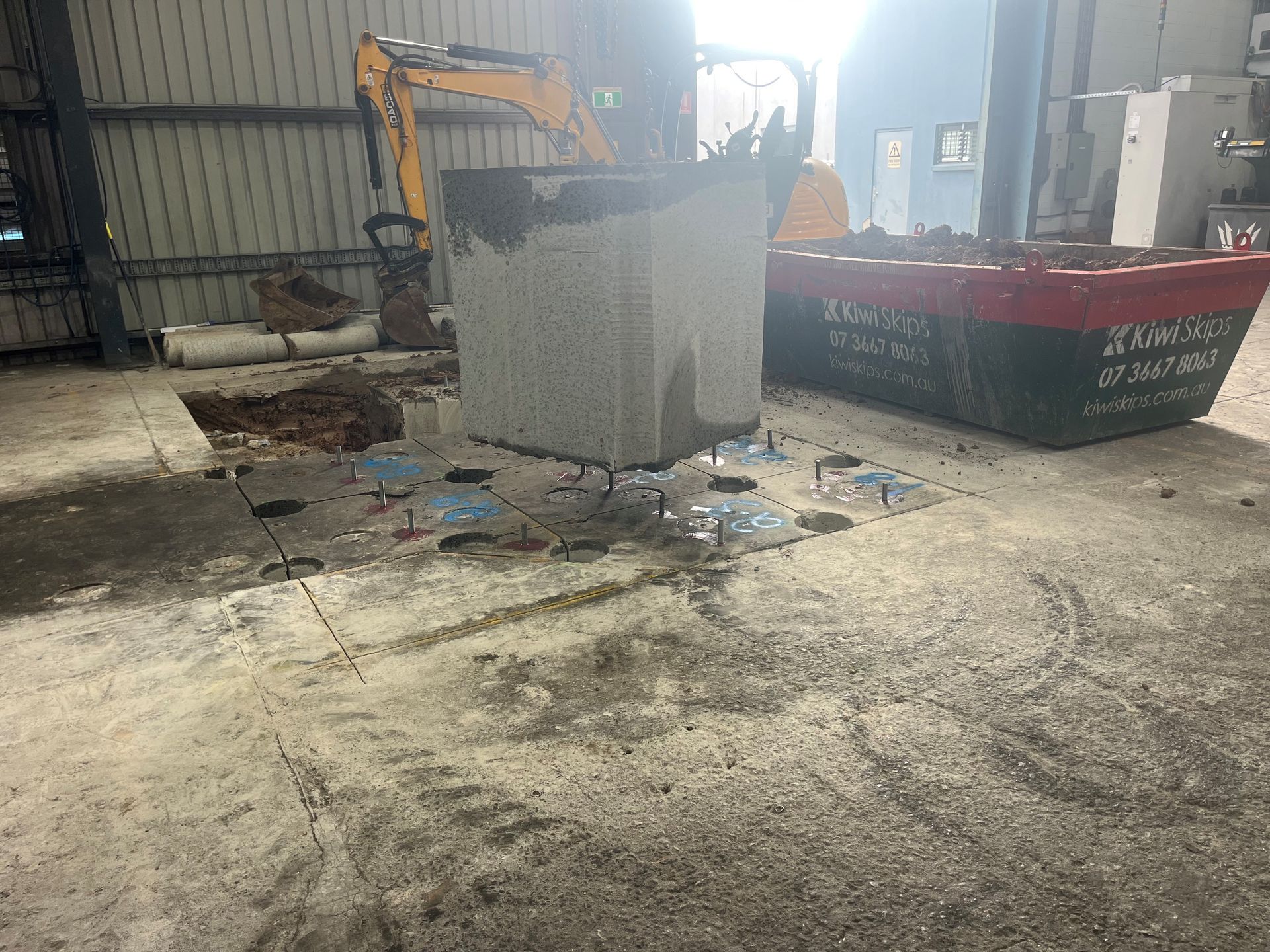 A large concrete pillar is being demolished in a warehouse.