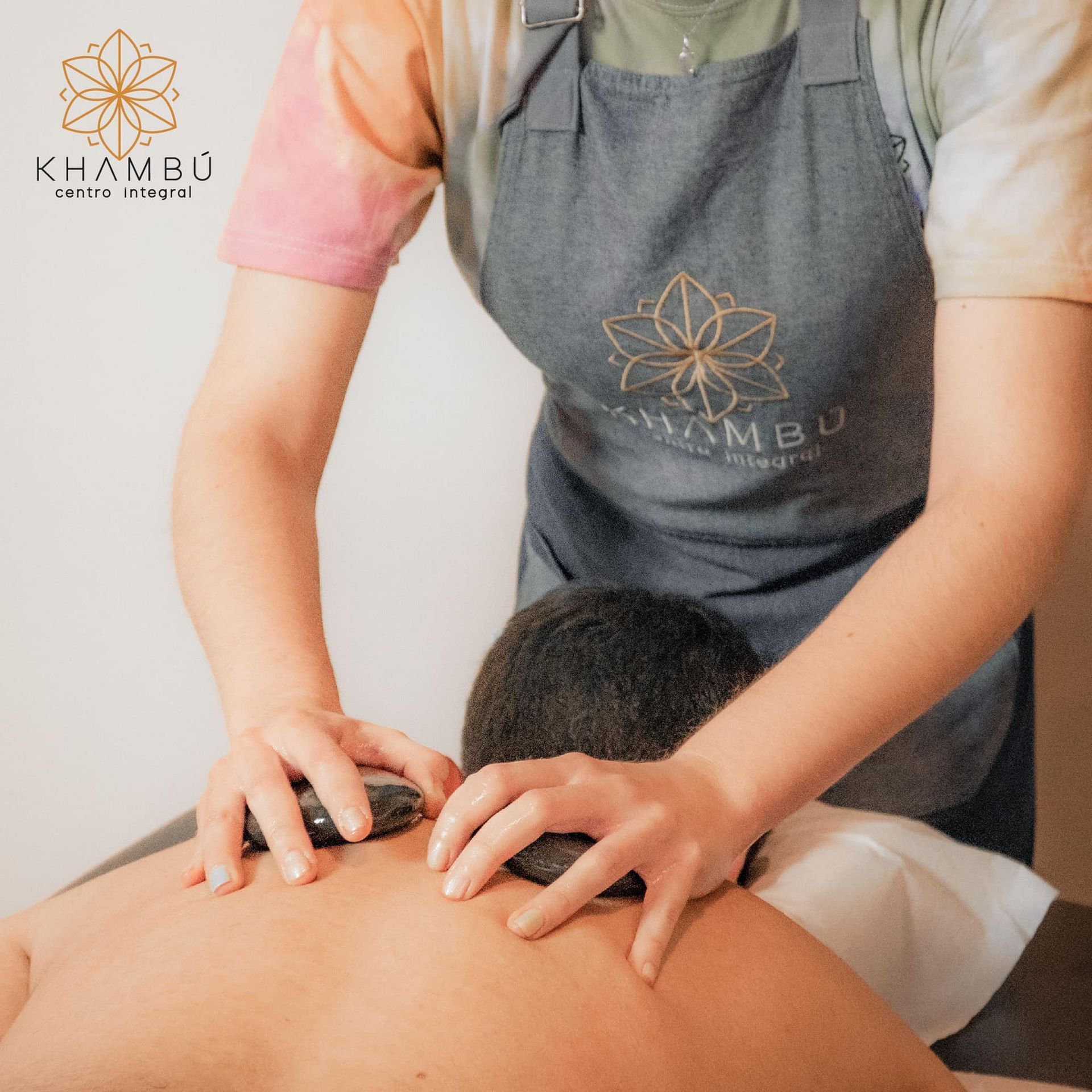 Una mujer le está dando un masaje a un hombre con piedras.