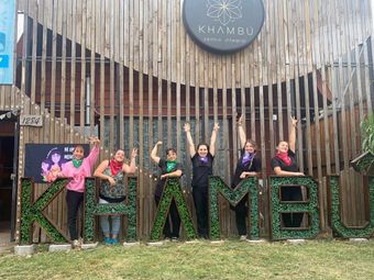 Un grupo de mujeres posa para una fotografía frente a un edificio de madera.