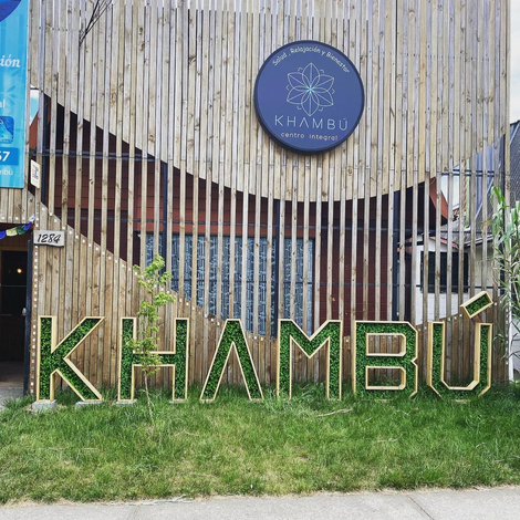 La palabra khambu está escrita en letras verdes en el césped frente a un edificio.