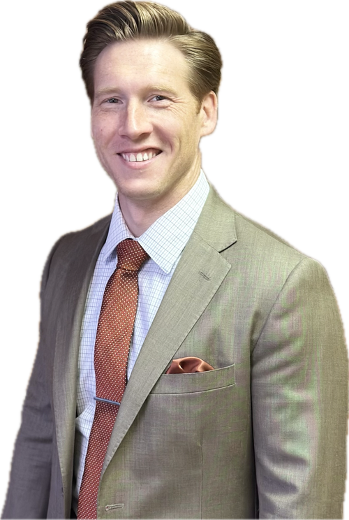 A smiling man in a light-brown suit and orange tie, with a pocket square, stands against a white background.