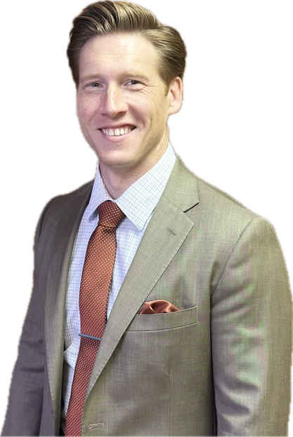 A smiling man in a light-brown suit and orange tie, with a pocket square, stands against a white background.