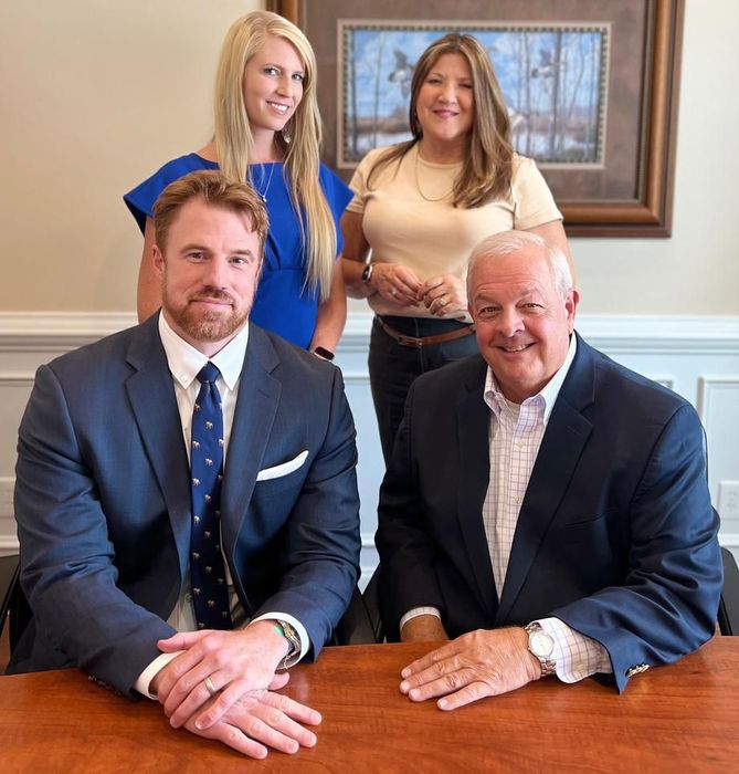 A group of people are posing for a picture while sitting at a table.