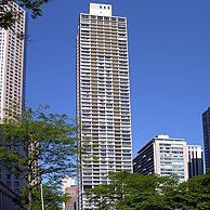 A tall building in the middle of a city surrounded by trees.