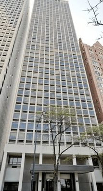 A tall building with a lot of windows and a tree in front of it.