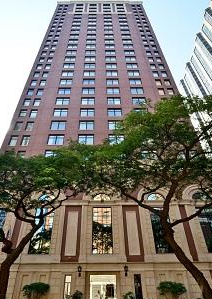 A tall brick building with lots of windows and trees in front of it.