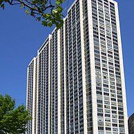 A tall building with a lot of windows is against a blue sky.