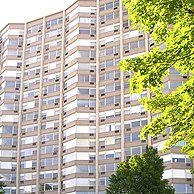 A tall building with a lot of windows and a tree in front of it.