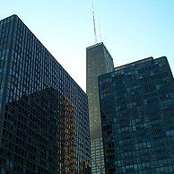 A group of tall buildings in a city with a blue sky in the background.