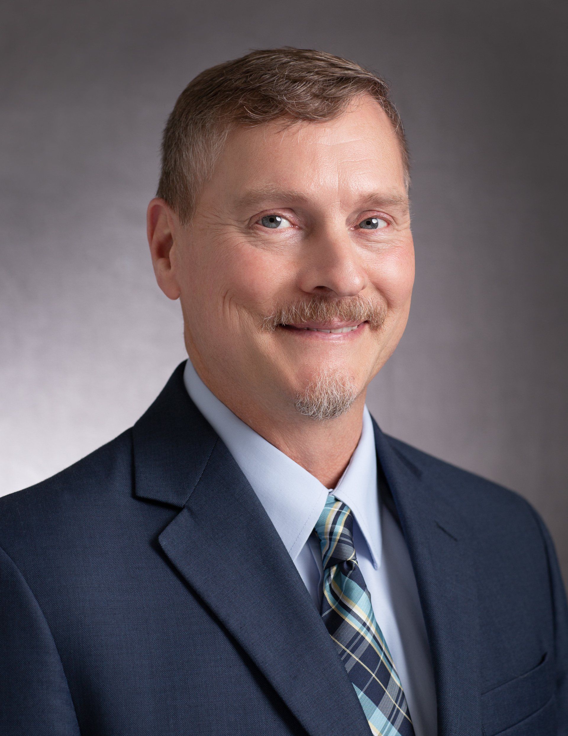 A man in a suit and tie is smiling for the camera.