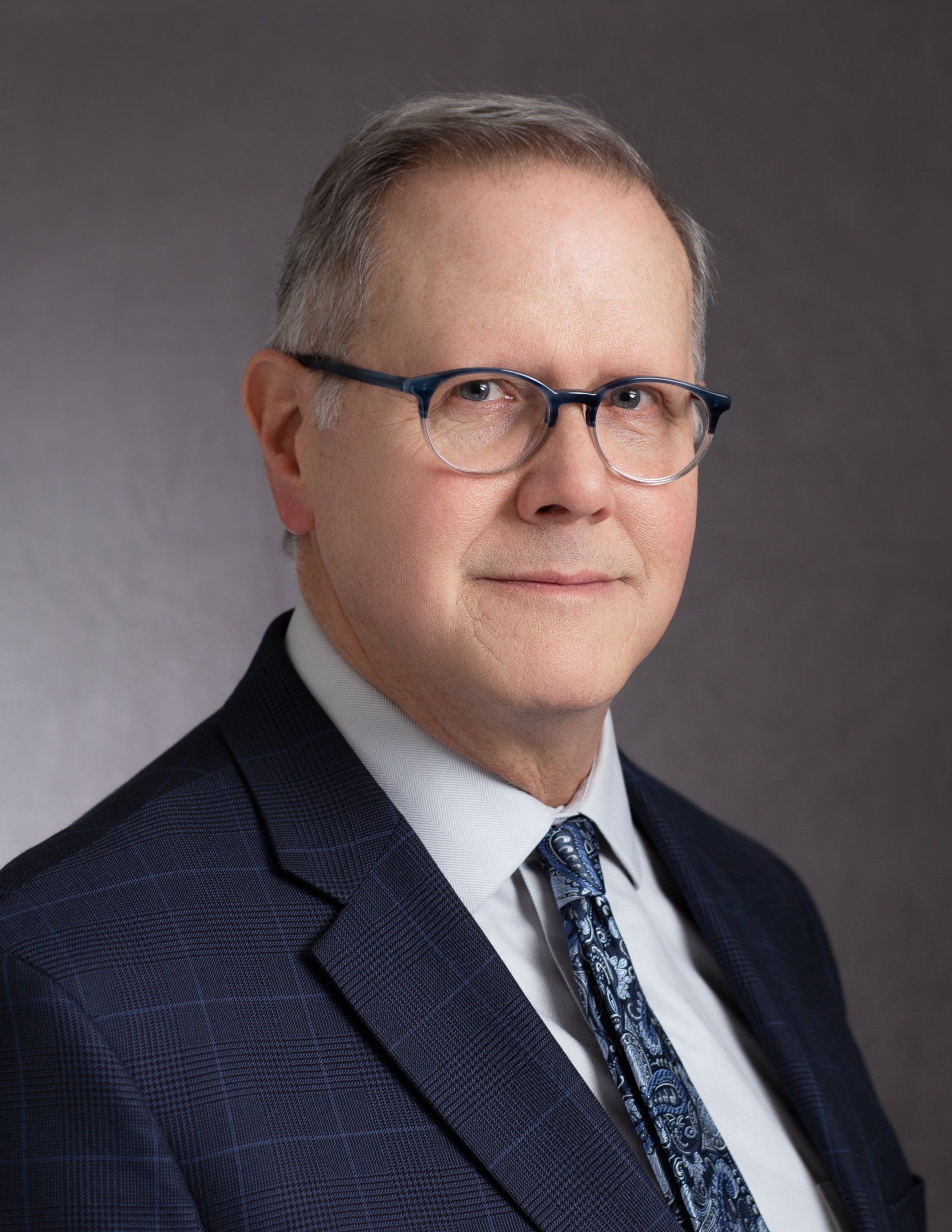 A man in a suit and tie is wearing glasses.