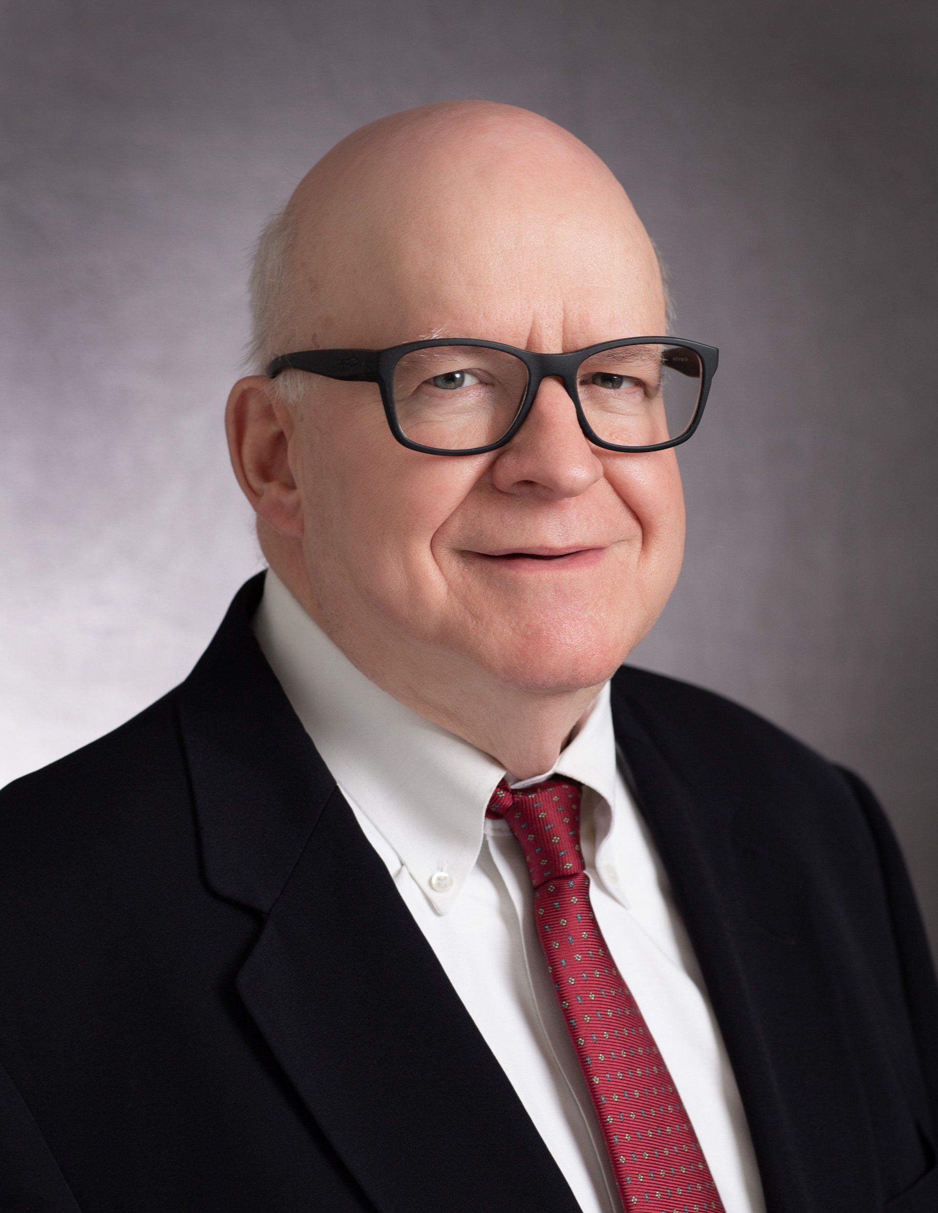A bald man wearing glasses and a suit and tie