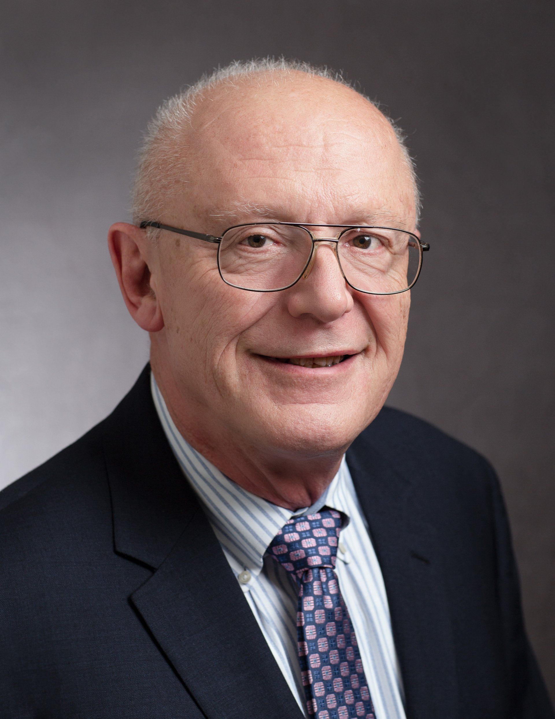 A man in a suit and tie is smiling for the camera