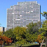 A large building is surrounded by trees in a park.