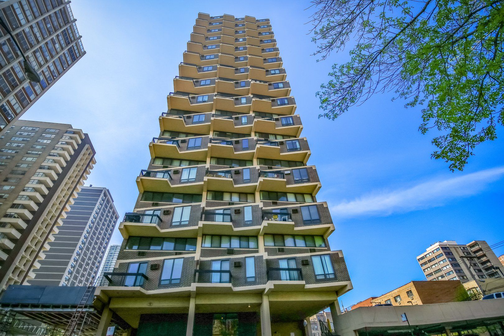 A tall building with a lot of windows is surrounded by other buildings in a city.