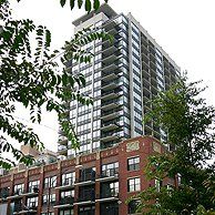 A tall building with a lot of windows is surrounded by trees.