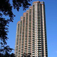 A tall building with a blue sky in the background and trees in the foreground.