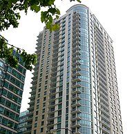 A tall building with a lot of windows is surrounded by other buildings.