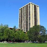 A tall building is surrounded by trees and grass in a park.