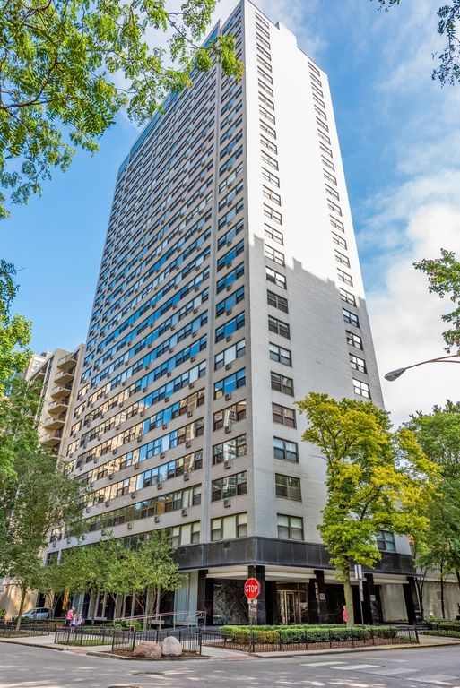 A tall building with a lot of windows is sitting on the corner of a city street.
