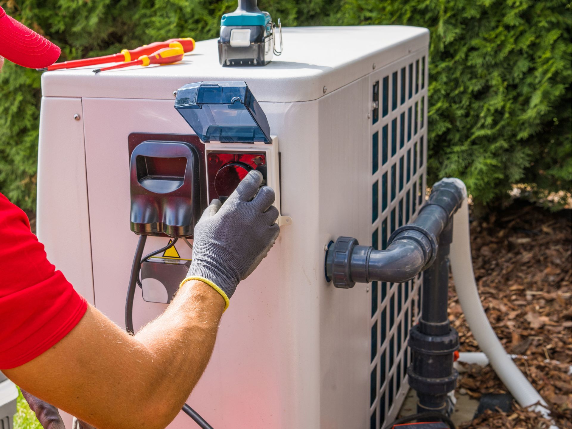 A man is working on an air conditioner outside of a house.