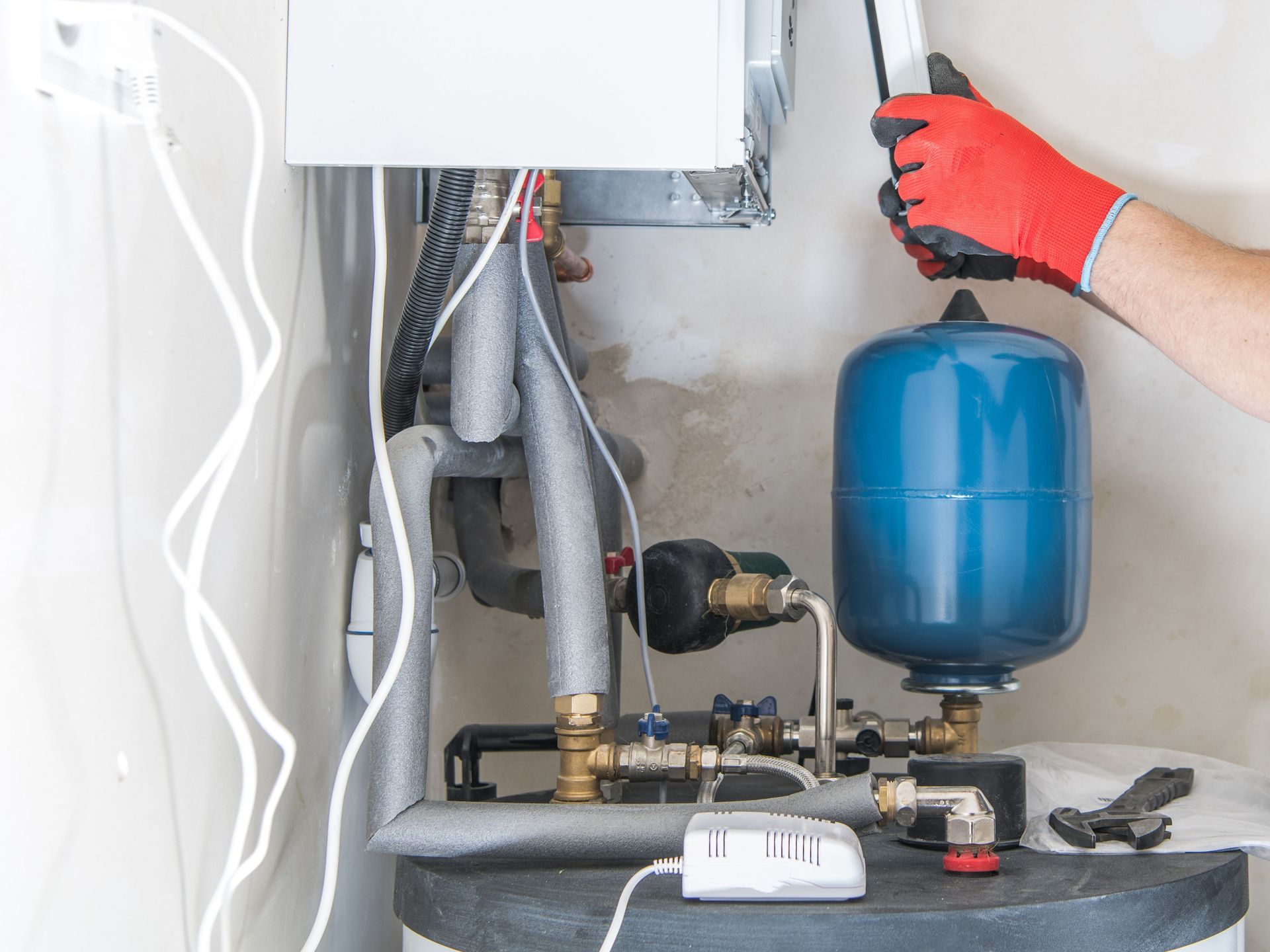 A person is working on a water heater in a room.
