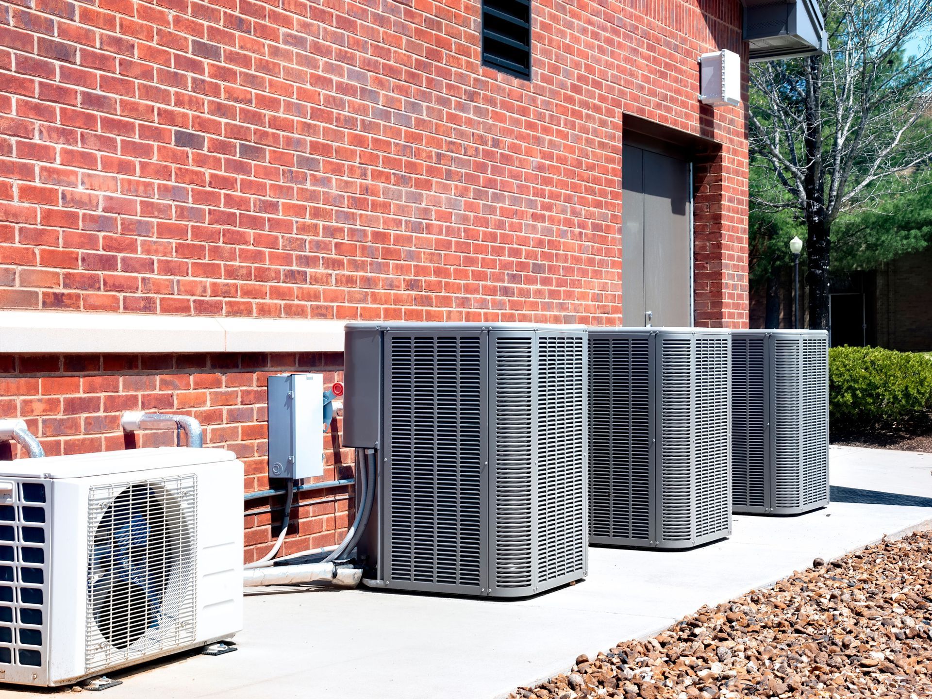 A row of air conditioners are sitting outside of a brick building.