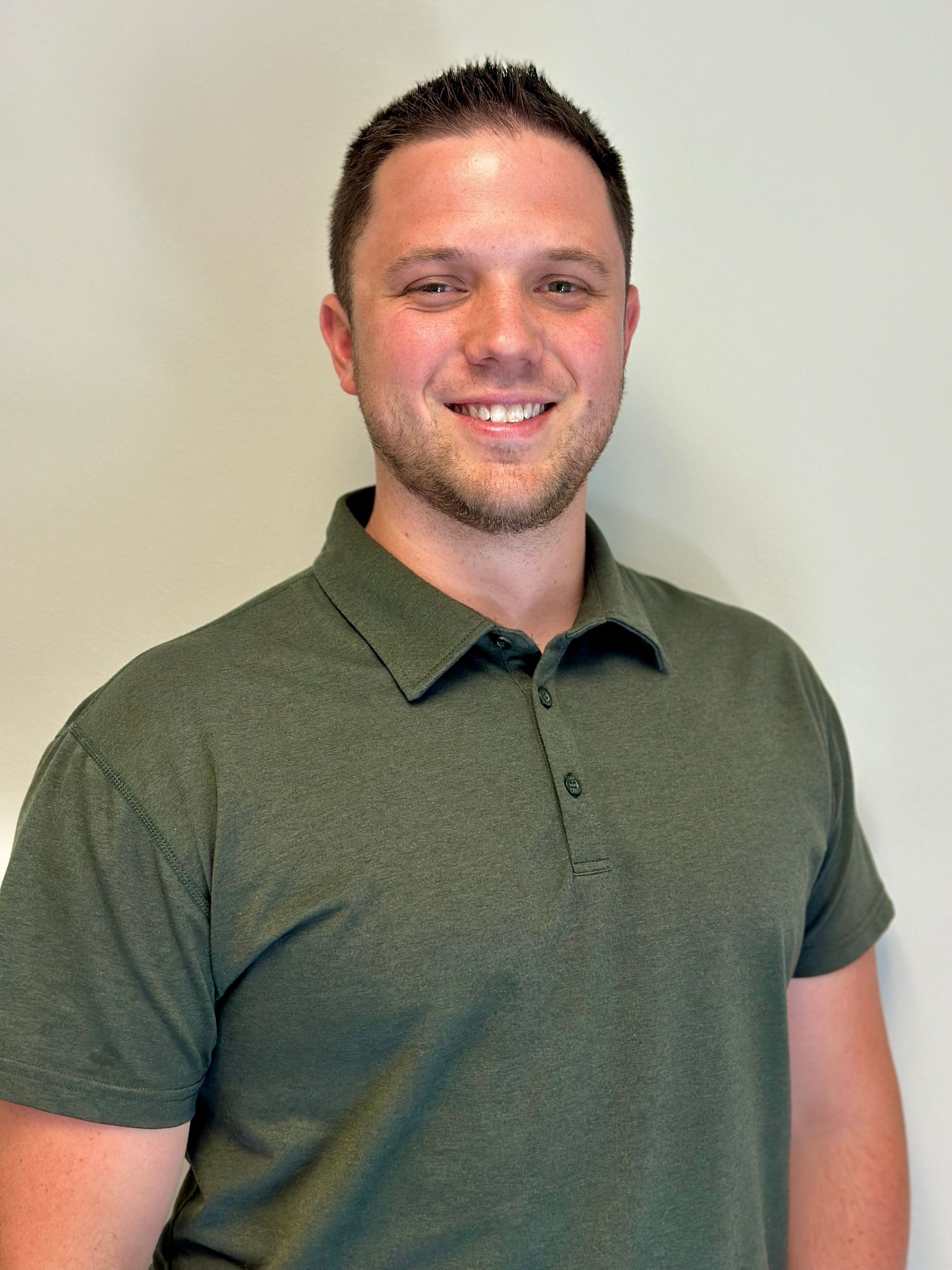 A man in a green polo shirt is smiling for the camera.
