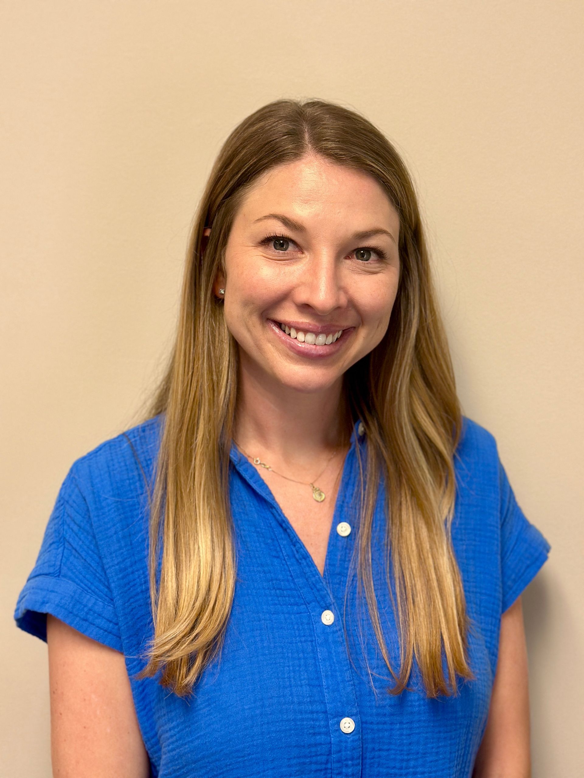 A woman in a blue shirt is smiling for the camera.