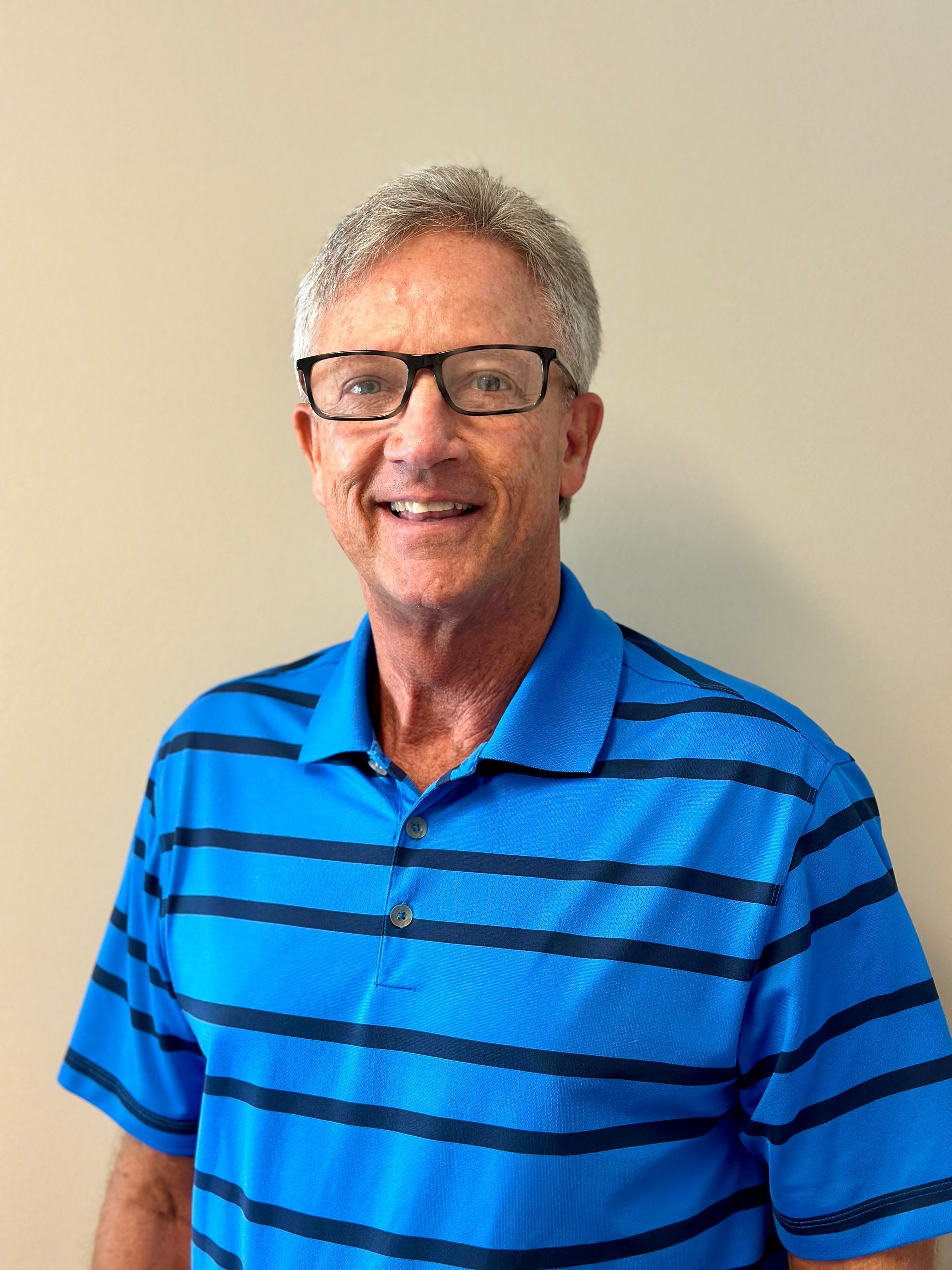 A man wearing glasses and a blue striped shirt is smiling for the camera.