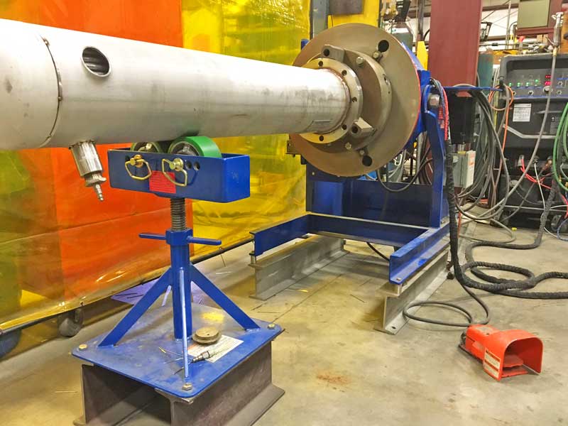 A large metal pipe is sitting on a machine in a factory.