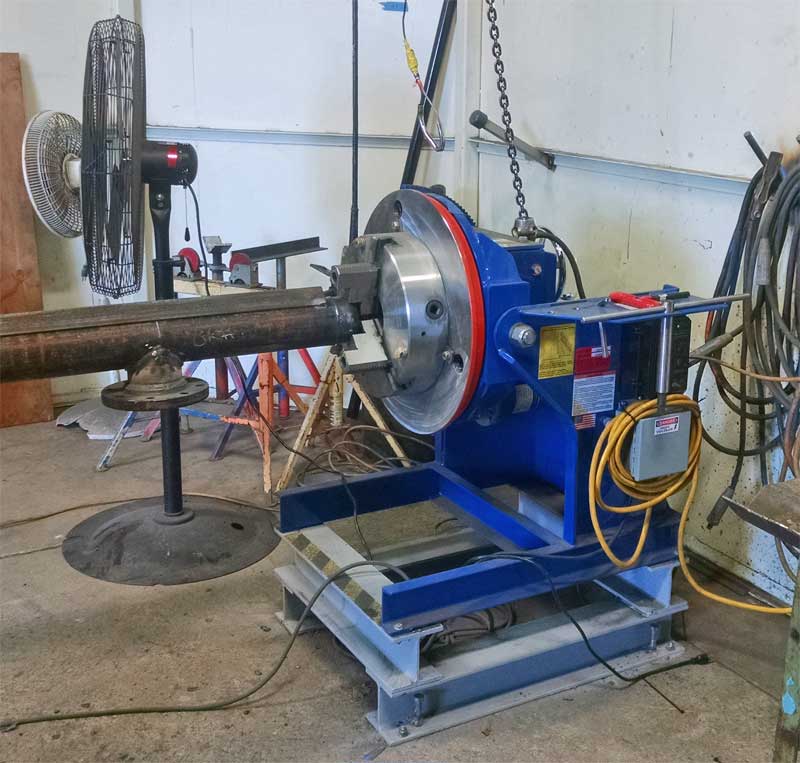 A blue machine is sitting in a room next to a fan