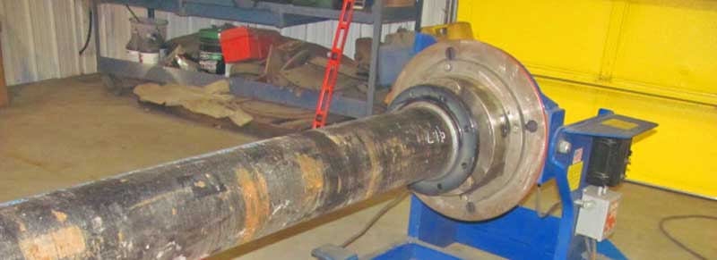 A large metal pipe is sitting on top of a machine in a garage.
