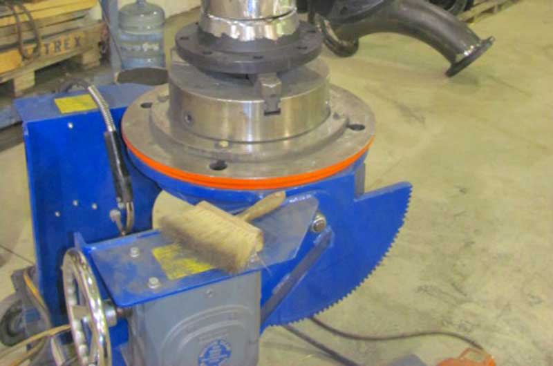 A blue machine is sitting on a concrete floor in a factory.