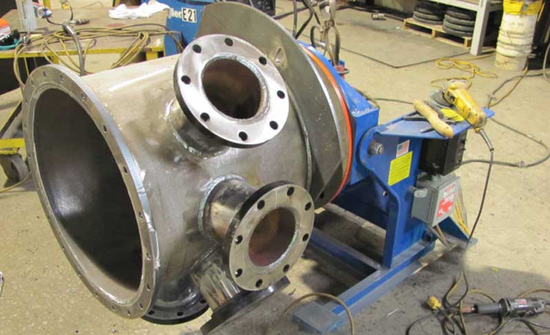 A large metal pipe is sitting on top of a blue machine