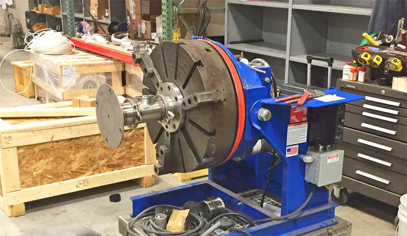 A blue machine is sitting on top of a pallet in a warehouse.