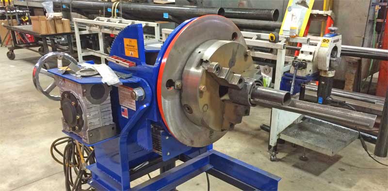 A blue machine is sitting in a factory next to a ladder.