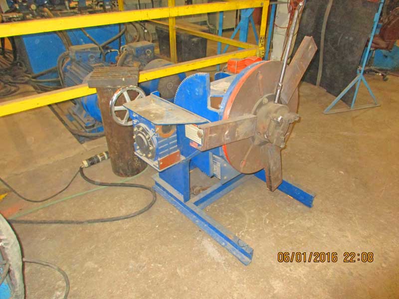 A machine is sitting on a concrete floor with a yellow railing behind it.