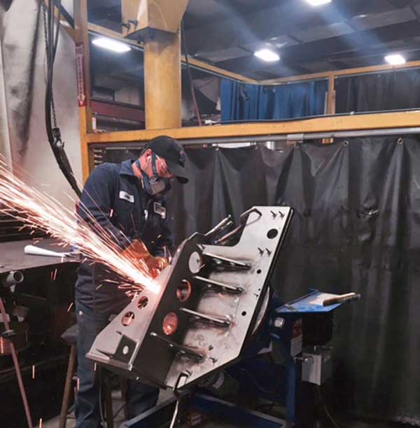 A man wearing a mask is welding a piece of metal