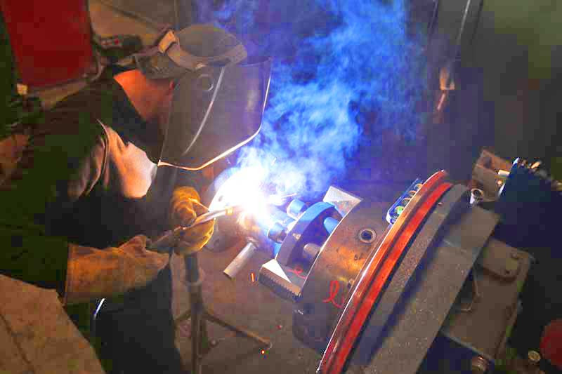 A man is welding a piece of metal in a factory.
